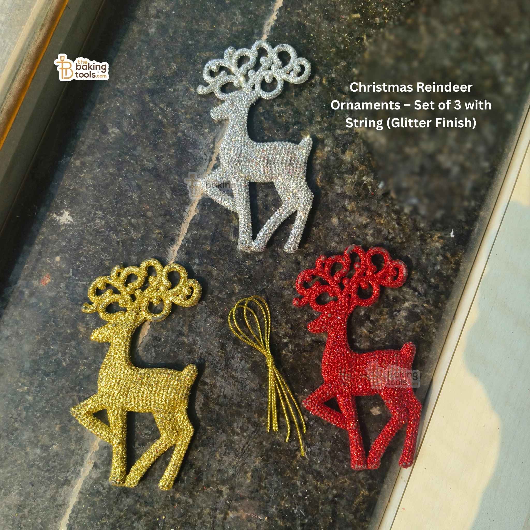 Set of three Christmas reindeer ornaments in gold, silver, and red on a dark surface.